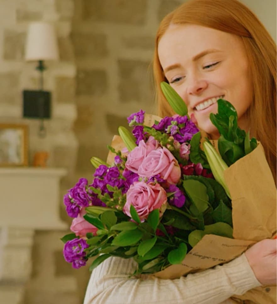 Smiling woman holding a Teleflora subscription bouquet